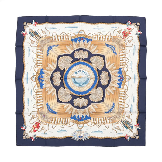 Hermès Carré 90 "RAILING" silk handkerchief in navy blue featuring a central ship deck motif with beige railings, scallop shells, golden ropes, and maritime flags on a nautical-themed background with clouds and waves.