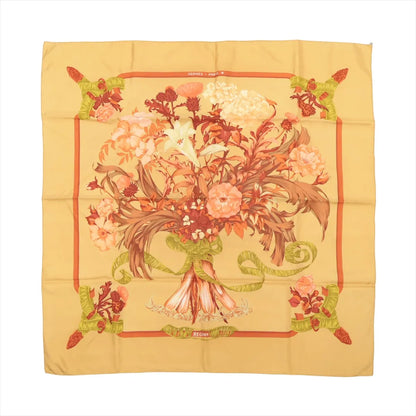 Hermès Carré 90 "Regina" silk scarf in yellow, featuring a large central bouquet of coral, cream, and peach flowers tied with a green ribbon, surrounded by a warm yellow background and floral corner accents.