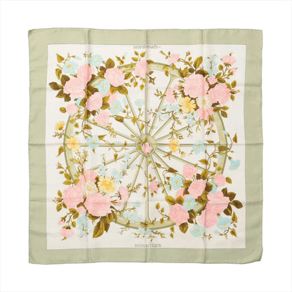 Hermès Carré 90 "Romantique" silk handkerchief in green, showcasing a central wheel motif surrounded by pink, yellow, and blue pastel flowers with green leaves on an ivory background, bordered by a soft sage green edge.