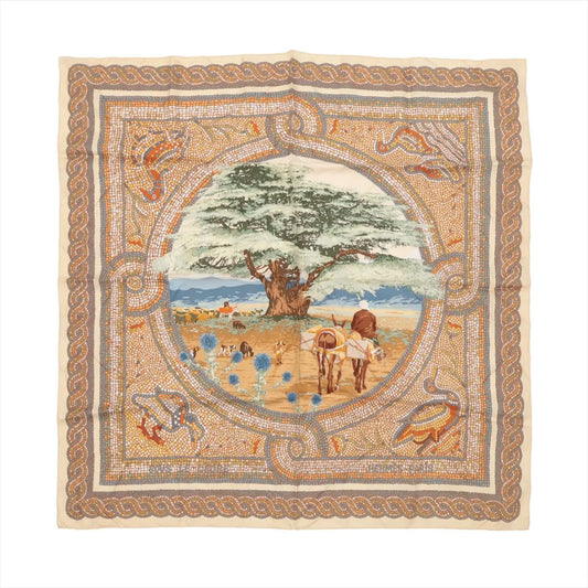 Flat-lay image of Hermès Carré 90 "Sous le Cèdre" silk scarf featuring a central pastoral scene with a large cedar tree, oxen, and shepherds, surrounded by a beige and multicolor mosaic-style border.