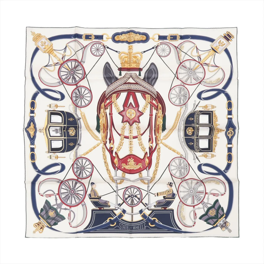 Top-down view of Hermès Carré 90 "Stately Wheels" silk handkerchief in ecru and blue, featuring detailed illustrations of royal carriages, harnesses, and reins in red, gold, and navy tones, symmetrically arranged around a central horse head motif.
