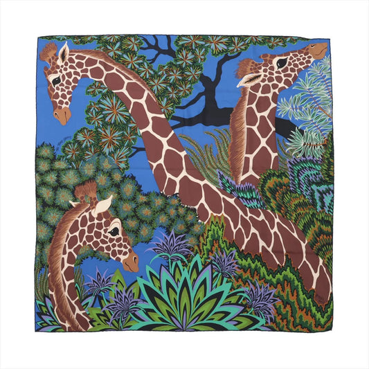 Hermès Carré 90 "THE THREE GRACES" silk scarf in navy blue, depicting three giraffes surrounded by dense jungle foliage in vivid greens, purples, and blues, set against a bold blue background with intricate hand-drawn detailing.