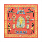 Hermès Carré 90 “Tutankhamun” silk scarf in orange with central pharaoh portrait and Egyptian motifs, framed by a yellow patterned border.