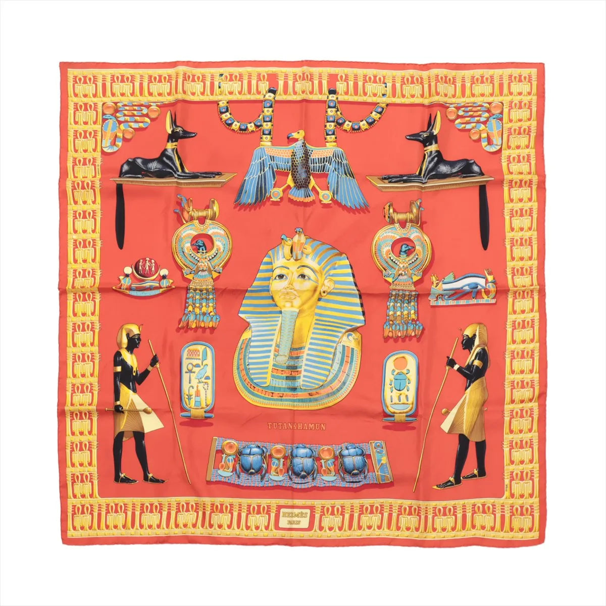 Hermès Carré 90 “Tutankhamun” silk scarf in orange with central pharaoh portrait and Egyptian motifs, framed by a yellow patterned border.