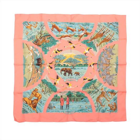 Hermès Carré 90 "Tanzanie" silk handkerchief in pink, featuring a vivid safari-inspired illustration with elephants, zebras, giraffes, lions, cheetahs, flamingos, and Maasai figures set against a landscape with Mount Kilimanjaro and acacia trees, bordered by a pink frame.