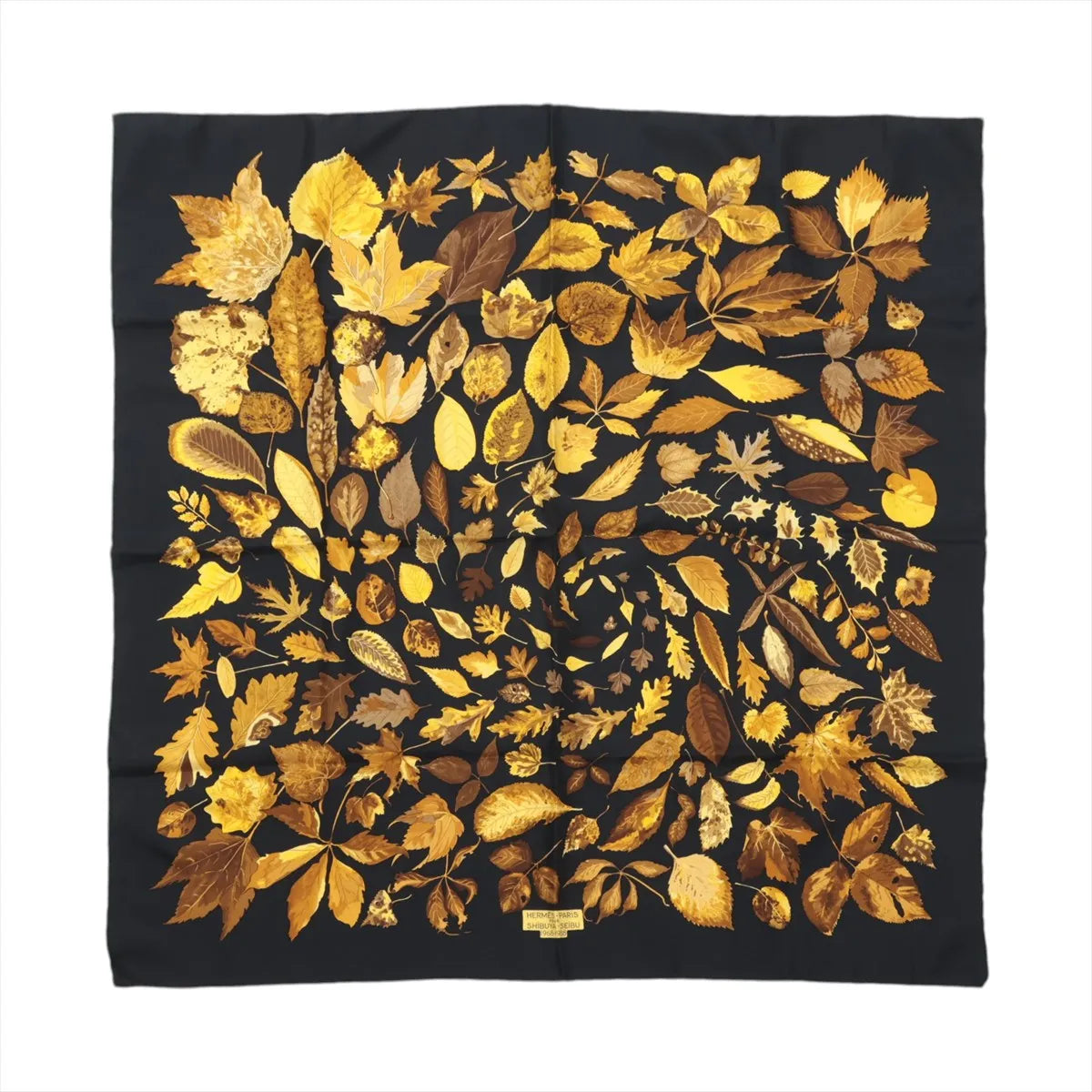 Hermès Carré 90 “Tourbillon” silk scarf in black with golden yellow and brown leaf motif arranged in a spiral pattern.