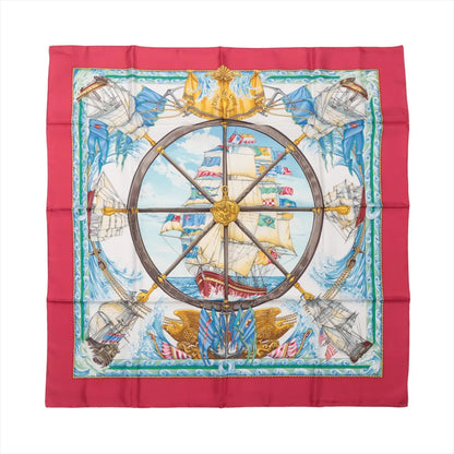 Hermès Carré 90 "VIVE LE VENT" silk scarf in red featuring central ship’s wheel design, detailed sailing ships, ocean waves, and maritime flags, bordered in vibrant red.