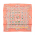 Flat-lay of a Hermès Carré 90 "Joyaux de l'Été" silk scarf in pink, featuring a symmetrical floral and butterfly motif in pastel shades with intricate detailing and a soft coral border.
