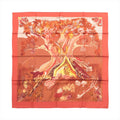 Hermès Kuggor Tree square scarf laid flat, with a coral-red border and a fantastical tree, mushrooms and plants in orange, yellow and burgundy tones.