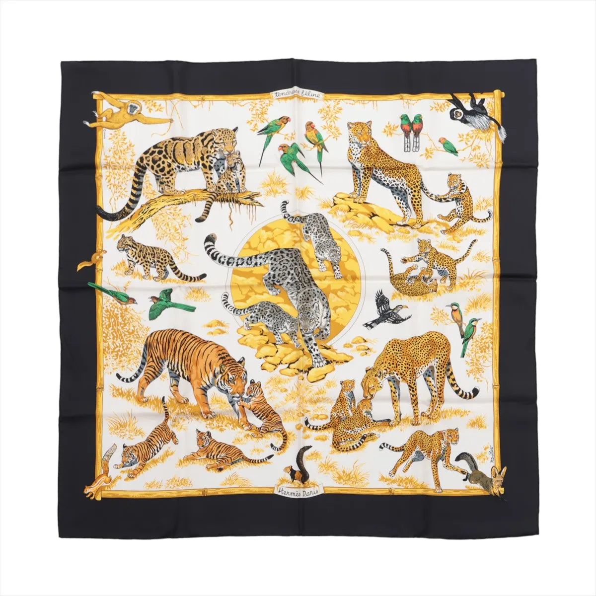 Hermès Carré 90 “Tendresse Féline” silk scarf in black and yellow, featuring a vivid jungle scene with leopards, tigers, cubs, parrots, and monkeys on a white background.