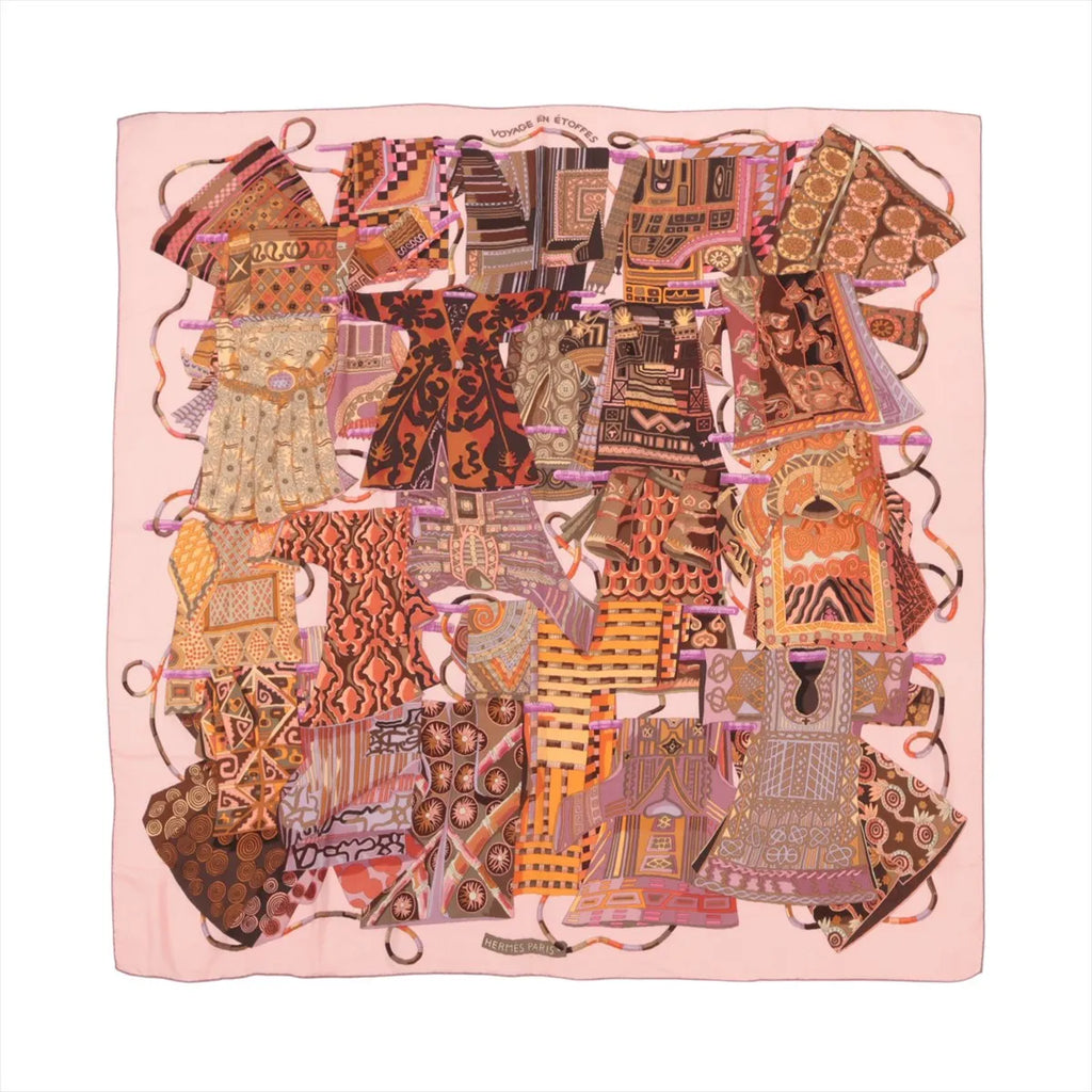 Hermès Carré 140 cashmere-silk scarf in pink with colorful textile collage pattern and “Voyage en Étoffes” title, laid flat on white background.