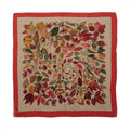 Hermès Carré Géant scarf with beige center, multicolor autumn leaf print in red, gold, green and brown, and a wide red border.