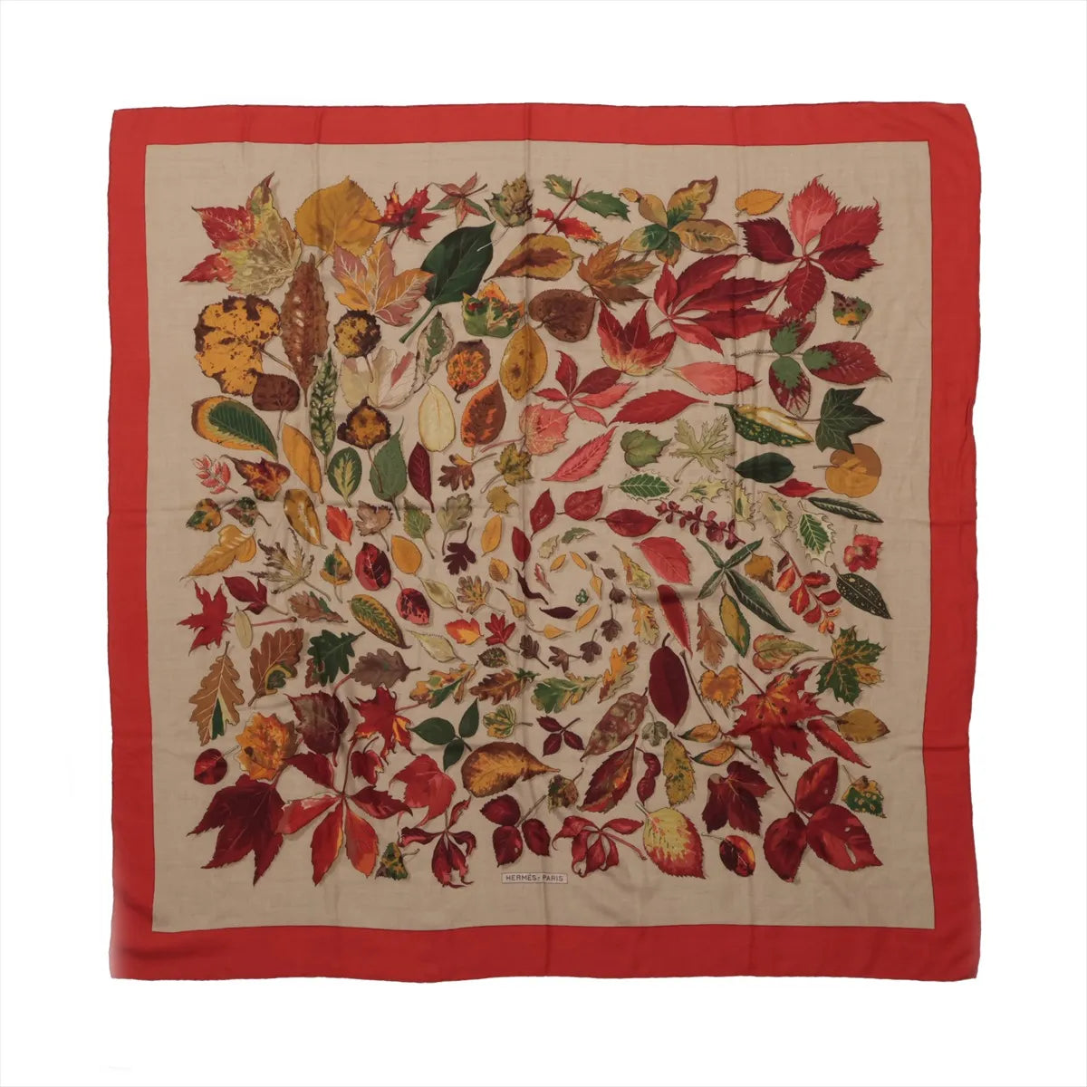 Hermès Carré Géant scarf with beige center, multicolor autumn leaf print in red, gold, green and brown, and a wide red border.