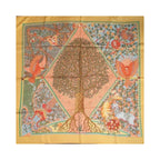 Hermès Axis Mundi square scarf laid flat, featuring a central tree with exposed roots, birds and floral motifs, framed by a golden-orange border.