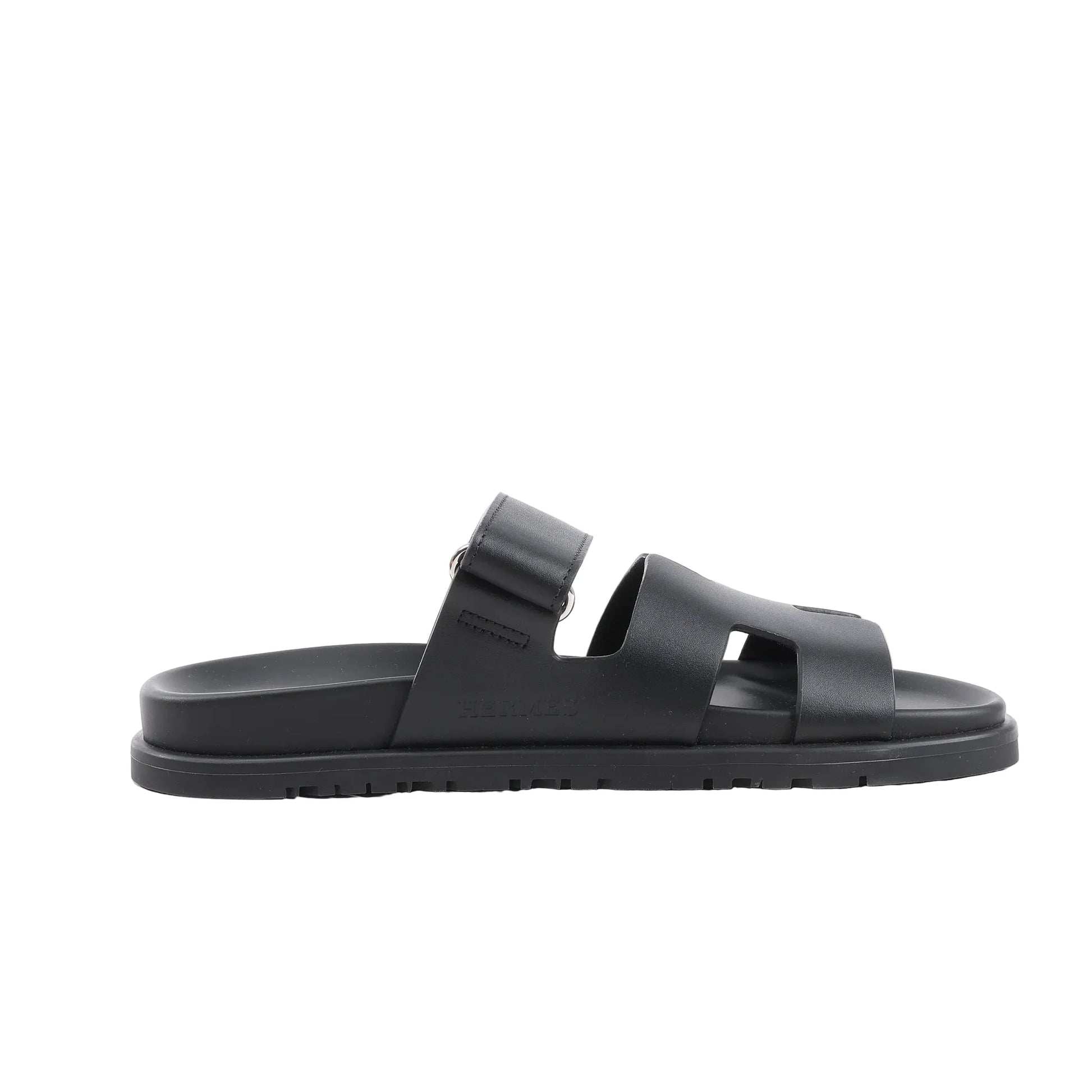 HERMÈS Cypre Leather Sandals in Black, Size 38.5 EU, featuring a smooth black leather upper with adjustable strap, signature “H” cut-out design, contoured footbed, and textured rubber sole, shown in a side profile against a white background.