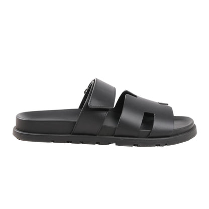 HERMÈS Cypre Sandals in black smooth leather, size 42 EU, featuring a wide cutout strap design, adjustable velcro strap, and flat sole, displayed on a white background.