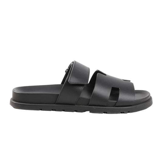 HERMÈS Cypre Sandals in black smooth leather, size 42 EU, featuring a wide cutout strap design, adjustable velcro strap, and flat sole, displayed on a white background.