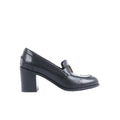 Black Hermès leather heeled loafers with orange-accent H hardware displayed beside an orange Hermès box, dust bag and paperwork.