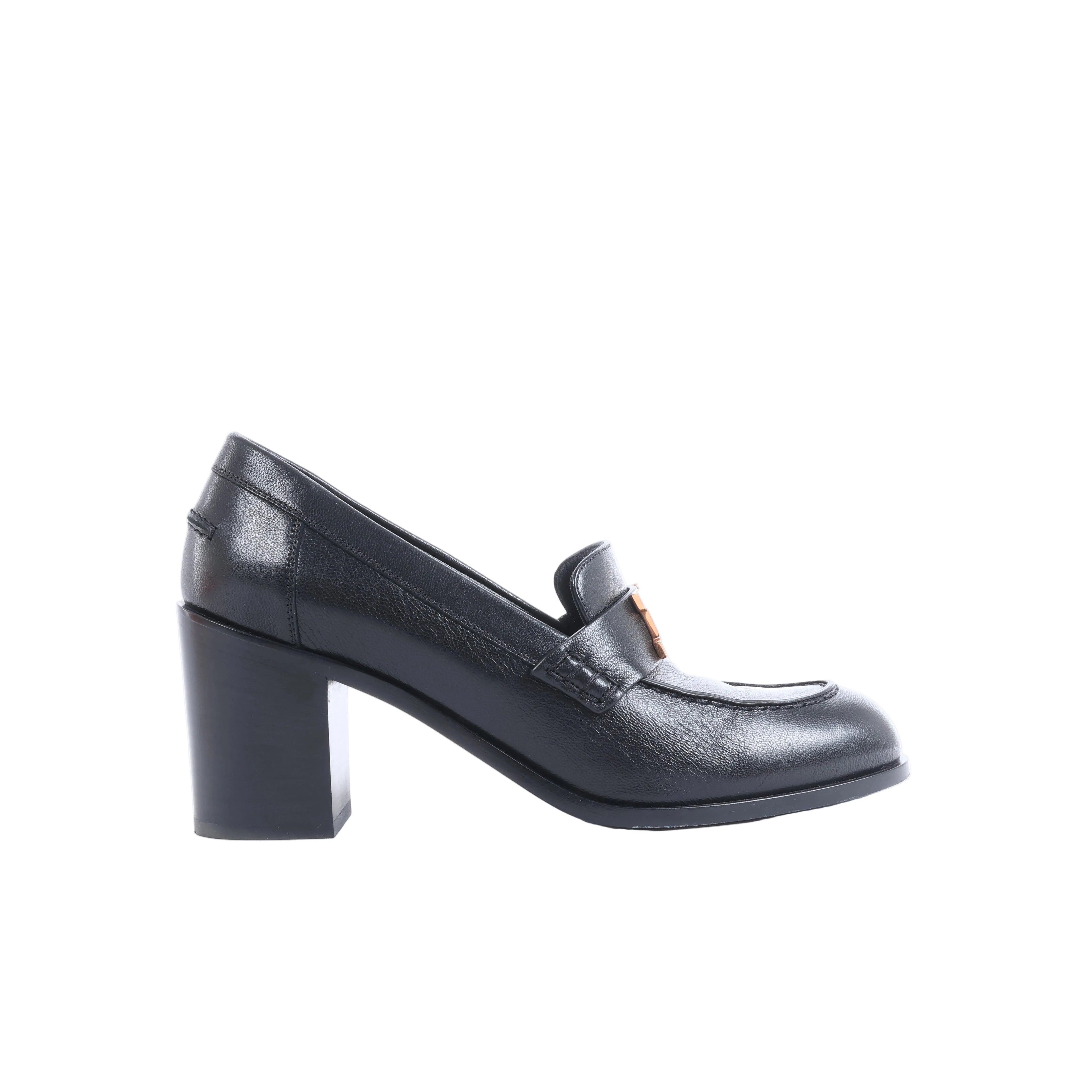 Black Hermès leather heeled loafers with orange-accent H hardware displayed beside an orange Hermès box, dust bag and paperwork.