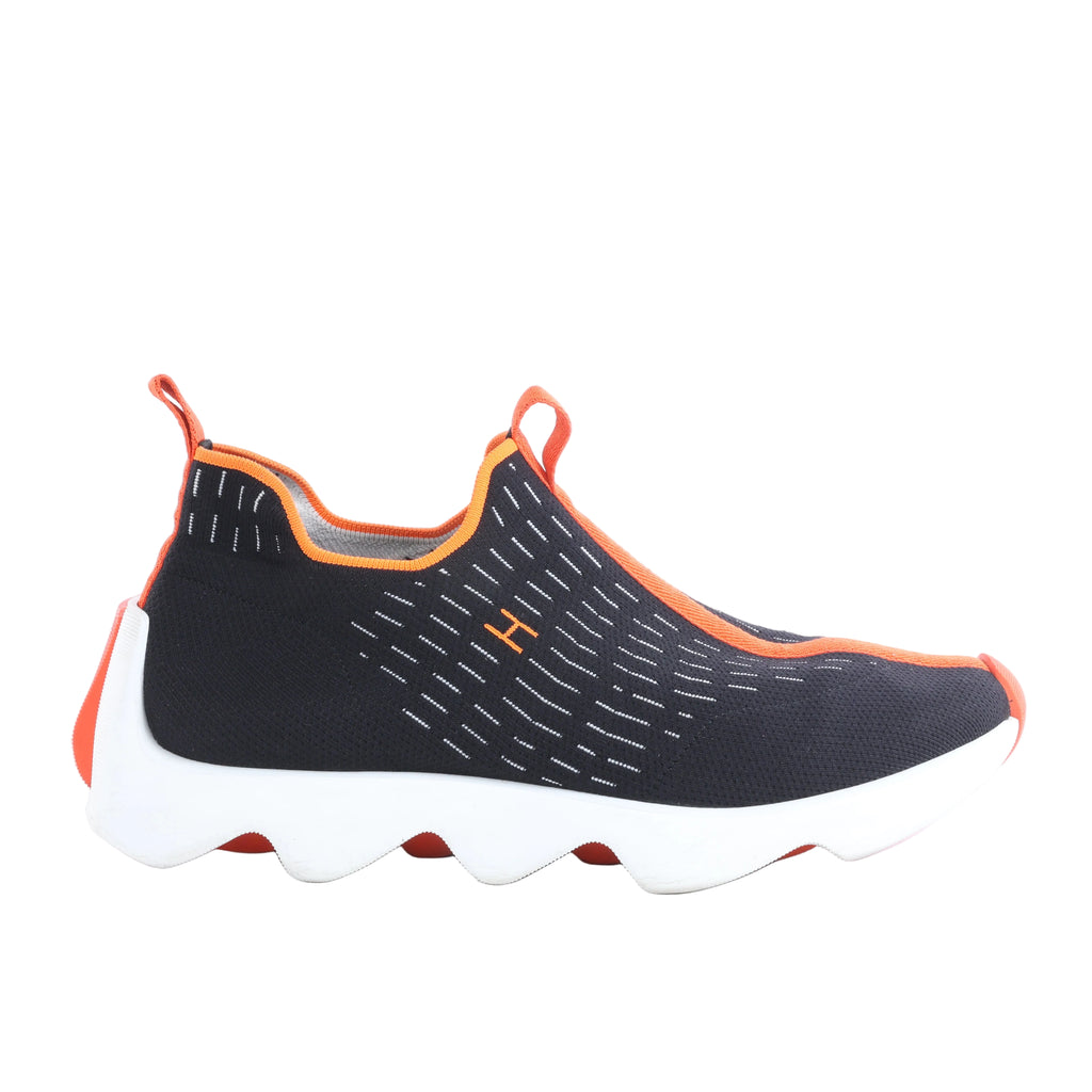 Hermès Eclair black fabric slip-on sneaker with orange trim, white stitched detailing, pull tabs and sculptural white sole.