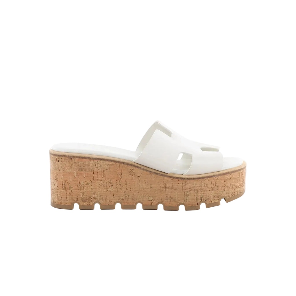 Hermès Eze white leather slide sandal with cutout H strap and cork platform wedge sole on white background