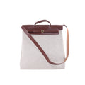 Hermès Herbag GM beige canvas bag with brown leather flap, top handle, long shoulder strap and gold-tone circular closure.