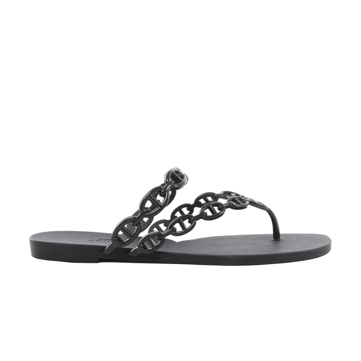 Side view of a black Hermès Island rubber sandal with glossy Chaîne d’Ancre chain-link straps, a toe post and a flat black sole.