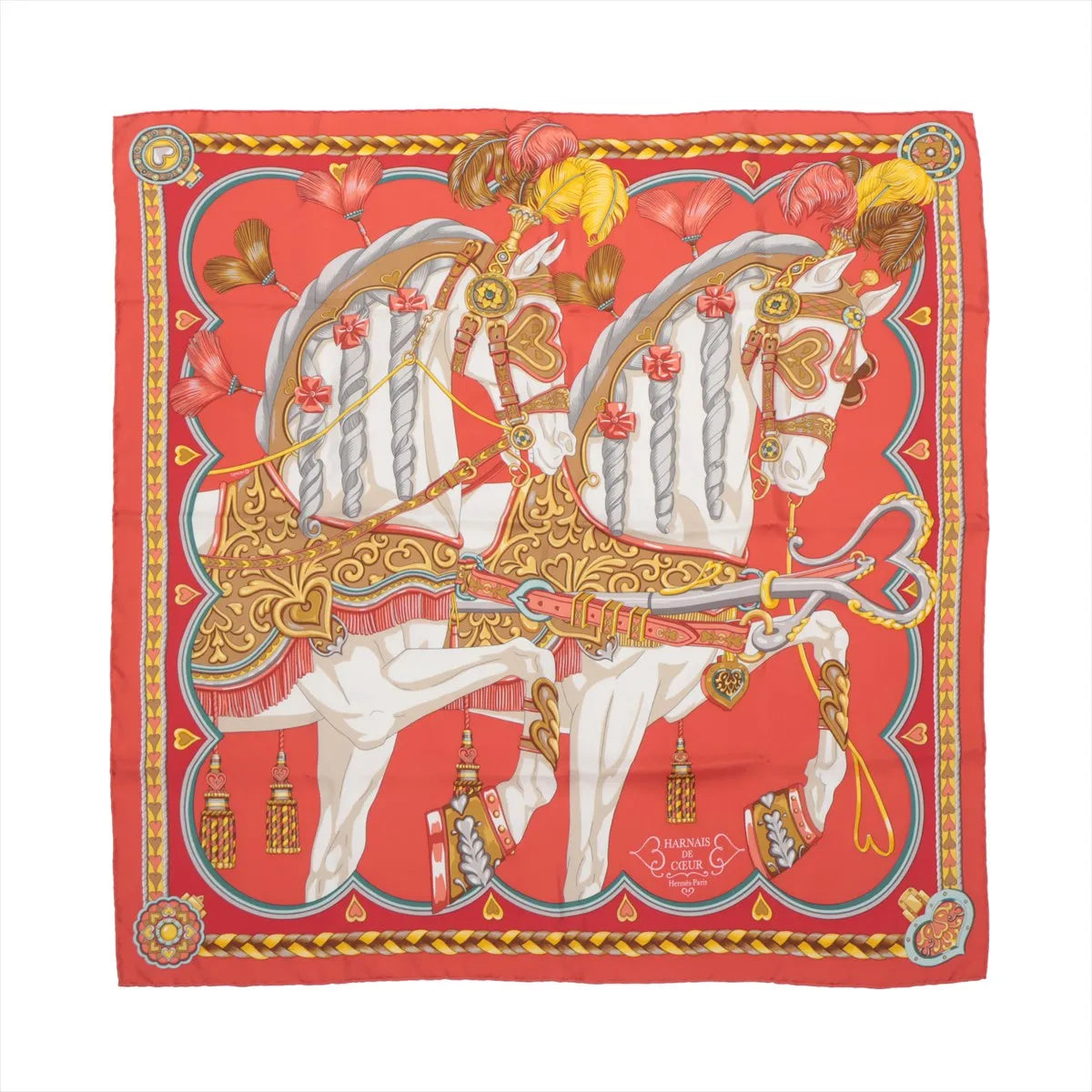 Hermès Carré 90 "Harnais de Coeur" silk handkerchief in red featuring two elaborately adorned white horses with gold heart-accented bridles, feathered plumes, and decorative tassels on a rich red background with a detailed yellow and red border.