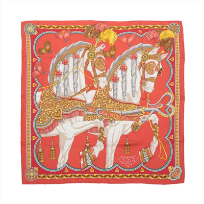 Hermès Carré 90 "Harnais de Coeur" silk handkerchief in red featuring two elaborately adorned white horses with gold heart-accented bridles, feathered plumes, and decorative tassels on a rich red background with a detailed yellow and red border.