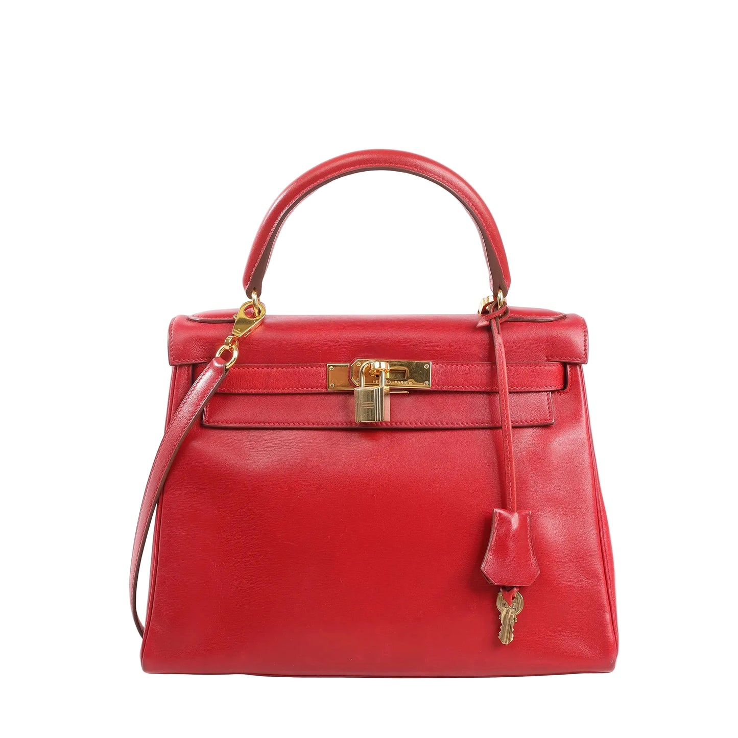 Front view of a red Hermès Kelly 28 Box leather handbag with top handle, detachable shoulder strap, gold turn-lock hardware, and hanging clochette with keys on a white background.