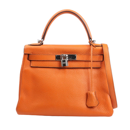 Front view of a Hermès Kelly 28 handbag in orange Taurillon Clemence leather, featuring a structured silhouette, top handle, silver-tone turn-lock closure with padlock, and leather clochette. Crafted in 2004 with the □H stamp.