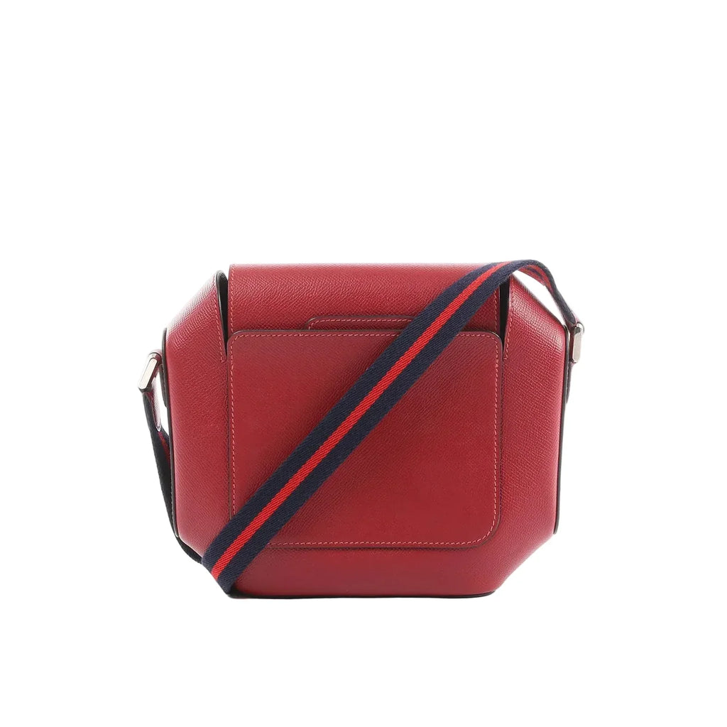 Hermès Octagon crossbody bag in red Epsom leather with a navy-and-red striped shoulder strap and silver-tone hardware on a white background.