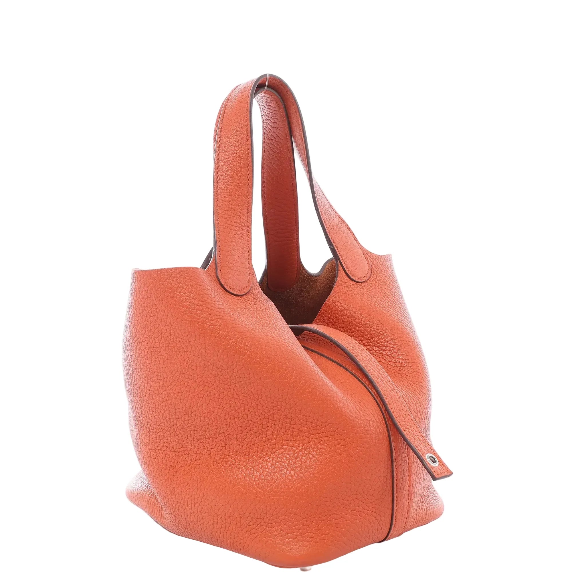 Hermès Picotin Lock 18 PM orange pebbled leather handbag with two top handles, open-top bucket shape, side strap, and silver-tone hardware on white background.