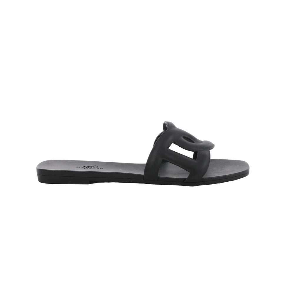 Black Hermès Aloha rubber slide sandal with sculpted cutout upper, flat sole and open-toe silhouette.
