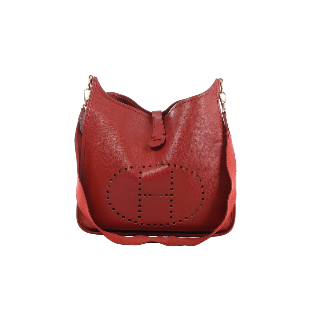 Red Hermès Evelyn GM leather shoulder bag with large perforated H motif, matching fabric strap, tab closure and gold-tone hardware.