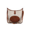 Front view of Hermès Evelyne I bag in beige canvas with brown leather trim, oval perforated H panel, brown shoulder strap and silver-tone hardware.