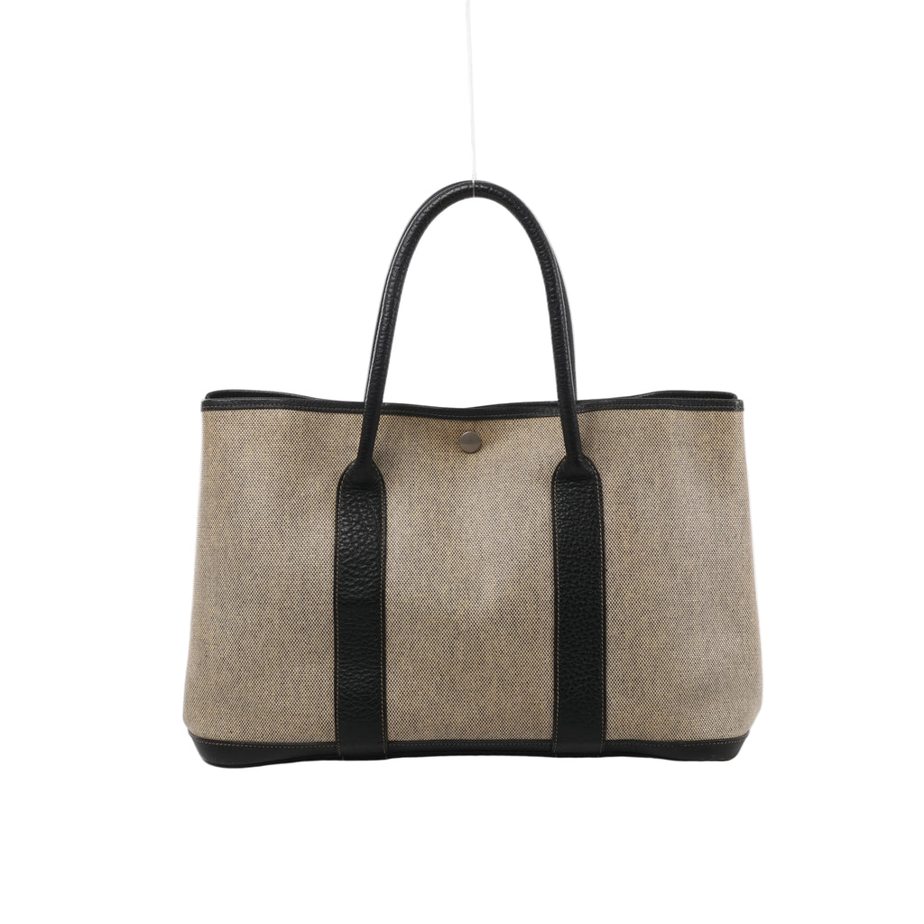 Beige Hermès Garden Party 36 PM canvas tote with dark brown leather handles and trim, vertical leather panels and silver-tone snap closure.