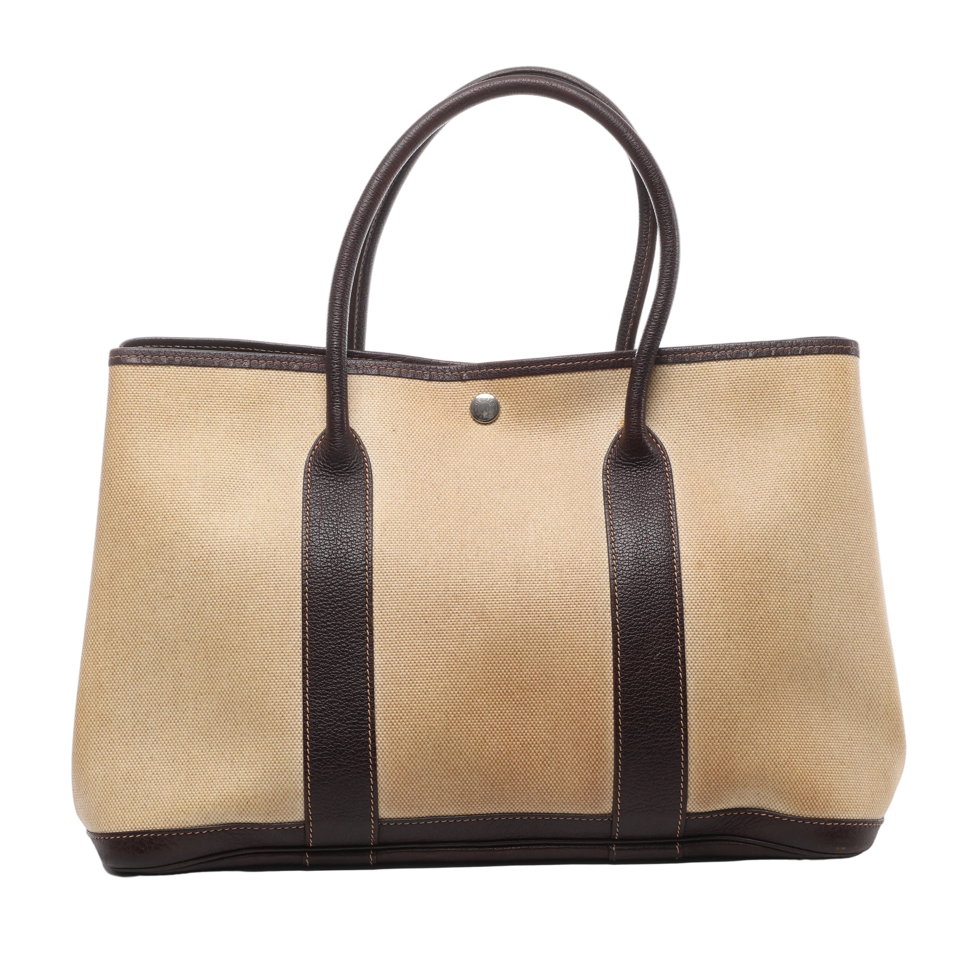 Hermès Garden Party 36 PM canvas tote with dark brown leather handles, vertical leather trim, base detailing and silver-tone snap closure.