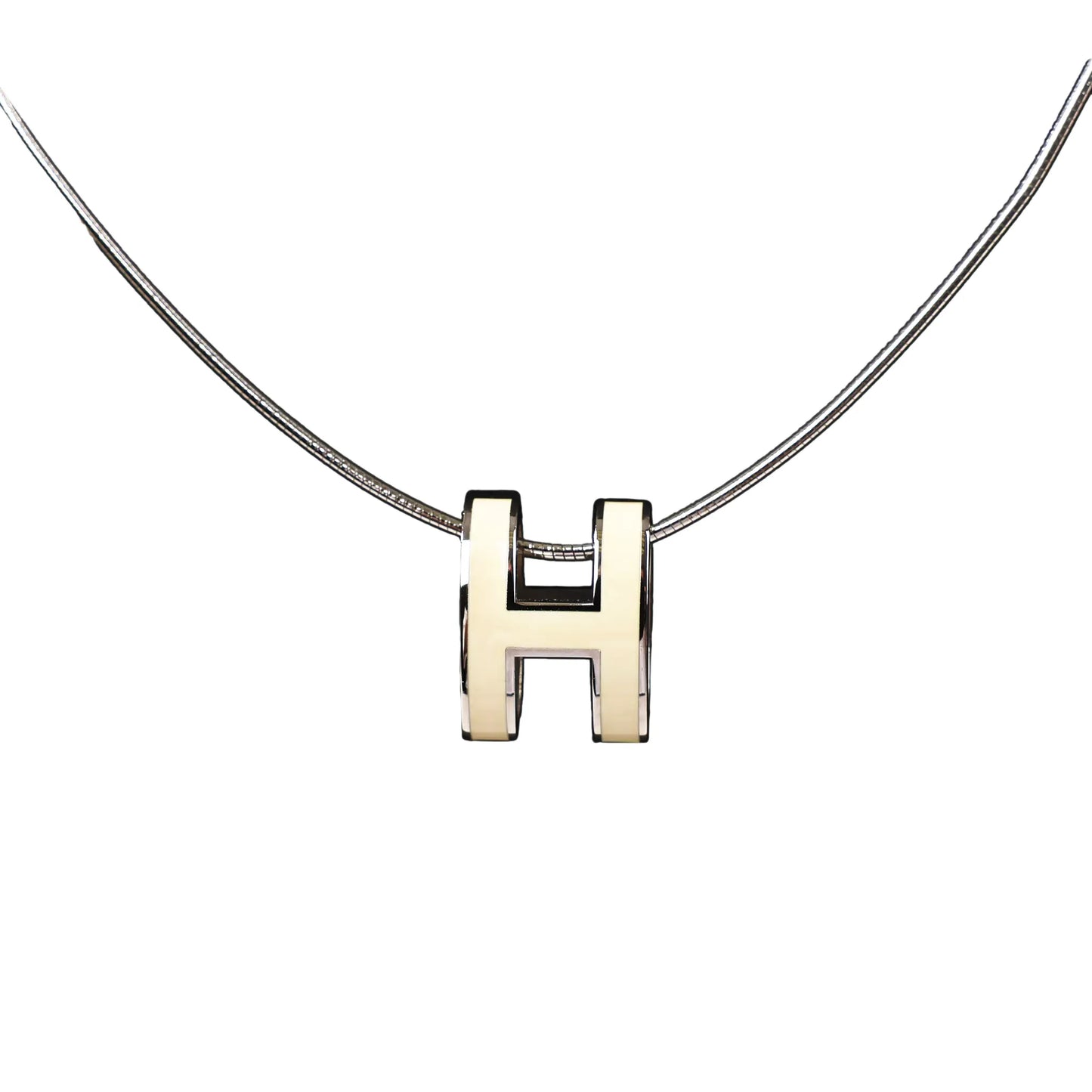 Close-up of a Hermès Pop H Necklace featuring an ecru enamel "H" pendant on a sleek silver chain, combining minimalist elegance with signature Hermès style.