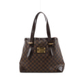 Brown Louis Vuitton Hampstead MM Damier Ebene shoulder bag with dark leather straps, reinforced corners and a gold-tone front nameplate.