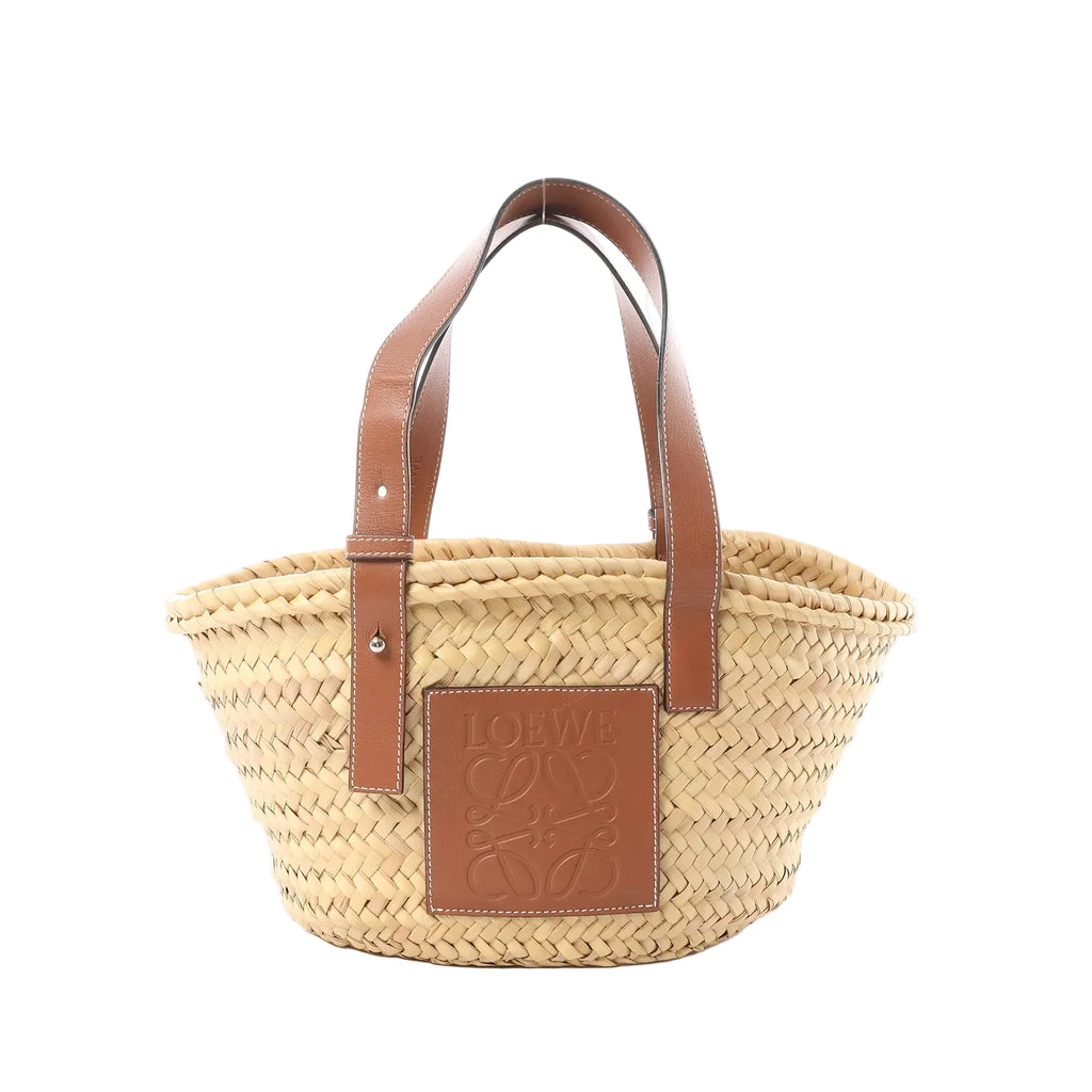 Front view of LOEWE Anagram Basket Small in beige woven raffia with brown leather shoulder straps and a brown leather Anagram logo patch.