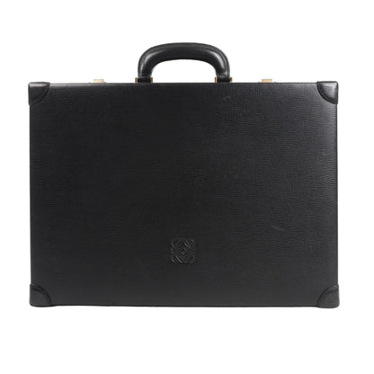 Loewe Anagram travel bag in black textured leather featuring a structured rectangular silhouette, top handle, reinforced leather corners, and embossed Anagram logo at the center, displayed against a white background.