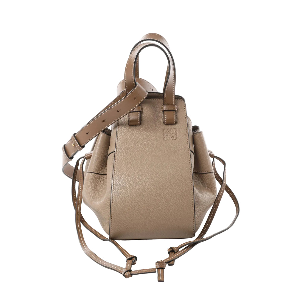 LOEWE Hammock Small beige grained leather handbag with embossed anagram logo, top handles, adjustable shoulder strap, and side tie straps on a white background
