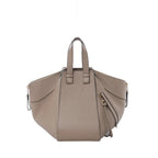 Loewe Hammock Small beige grained leather handbag with top handles, winged side panels, gold-tone zipper details, and embossed anagram logo on white background.