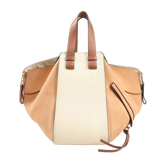 LOEWE Hammock Small Handbag in beige and brown leather with dual top handles, side zippers, gold-tone hardware, and sculptural expandable design against a white background.