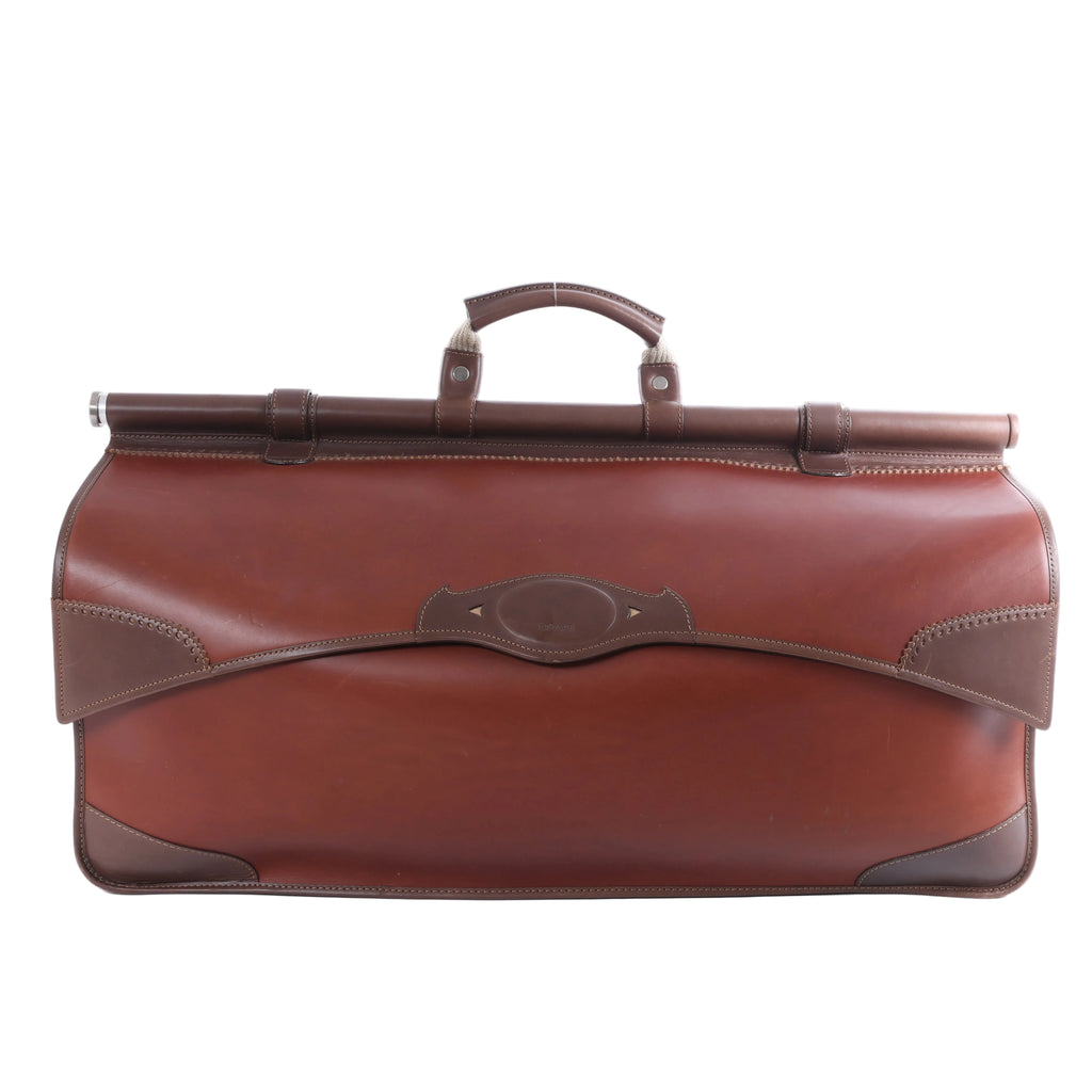 Brown Loewe leather travel bag with elongated structured body, darker brown trim, top handle and metal hardware on a white background.