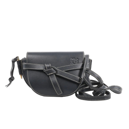 LOEWE Gate Mini Crossbody Bag in navy blue leather with white contrast stitching, knotted belt detail on the front, flap closure, and long adjustable leather strap, displayed against a white background.