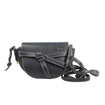 LOEWE Gate Mini Crossbody Bag in navy blue leather with white contrast stitching, knotted belt detail on the front, flap closure, and long adjustable leather strap, displayed against a white background.