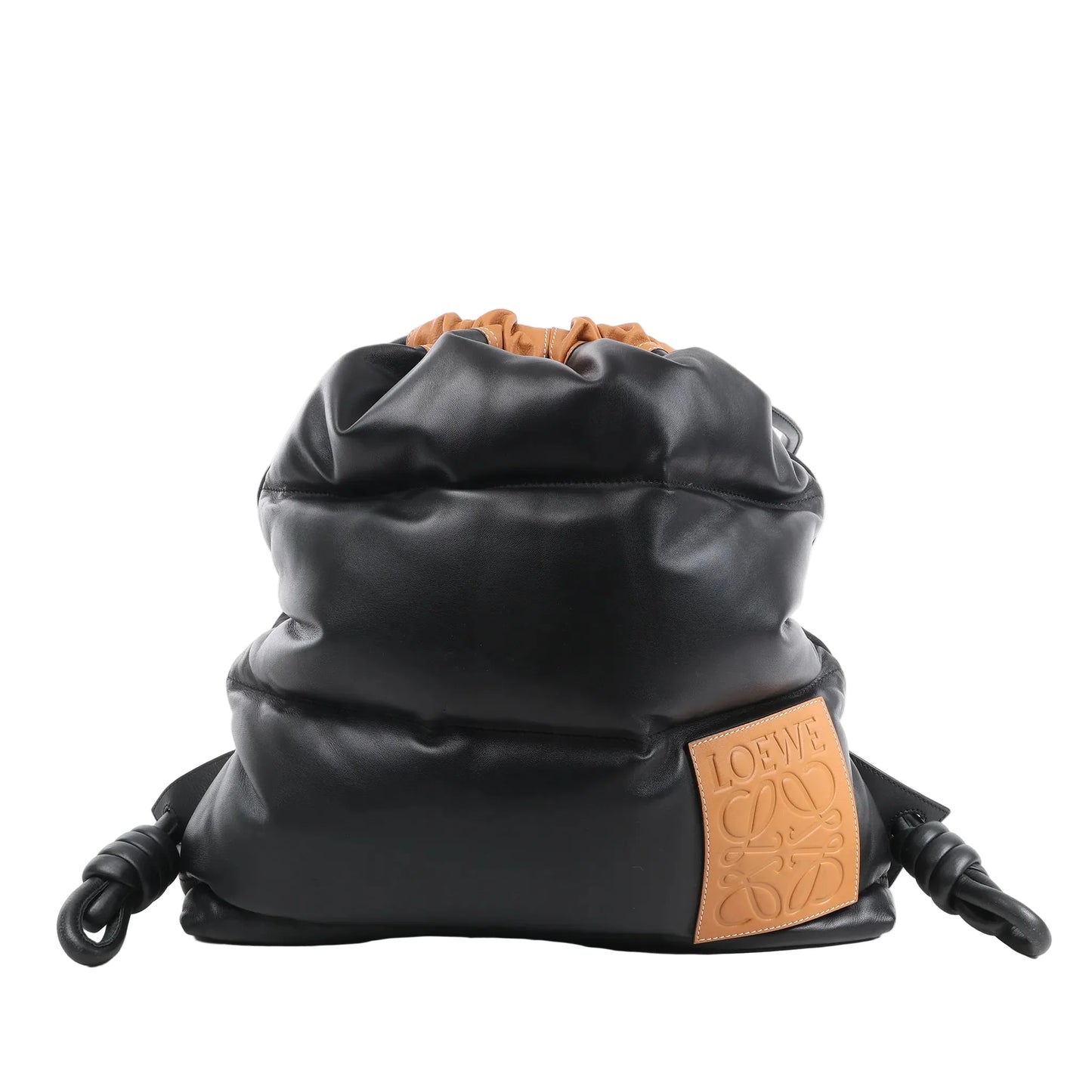 Front view of the LOEWE Puffy Yago Leather x Nylon Backpack in black and brown, showcasing a soft padded black leather exterior, brown drawstring closure, and tan leather logo patch with embossed LOEWE branding, displayed against a white background.