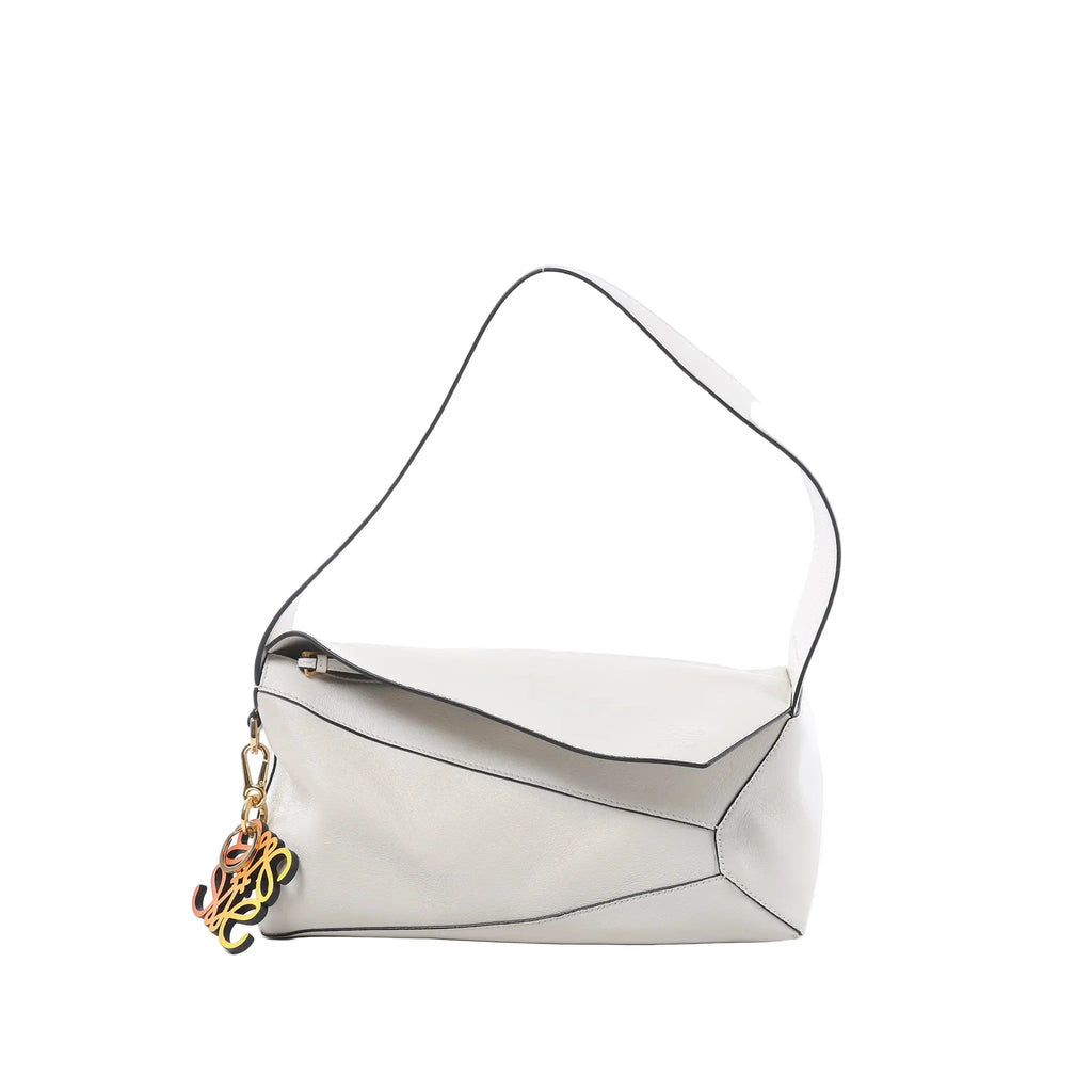 Loewe Puzzle Hobo shoulder bag in white leather with black edge trim, geometric paneling, slim shoulder strap, and colorful anagram charm on white background.